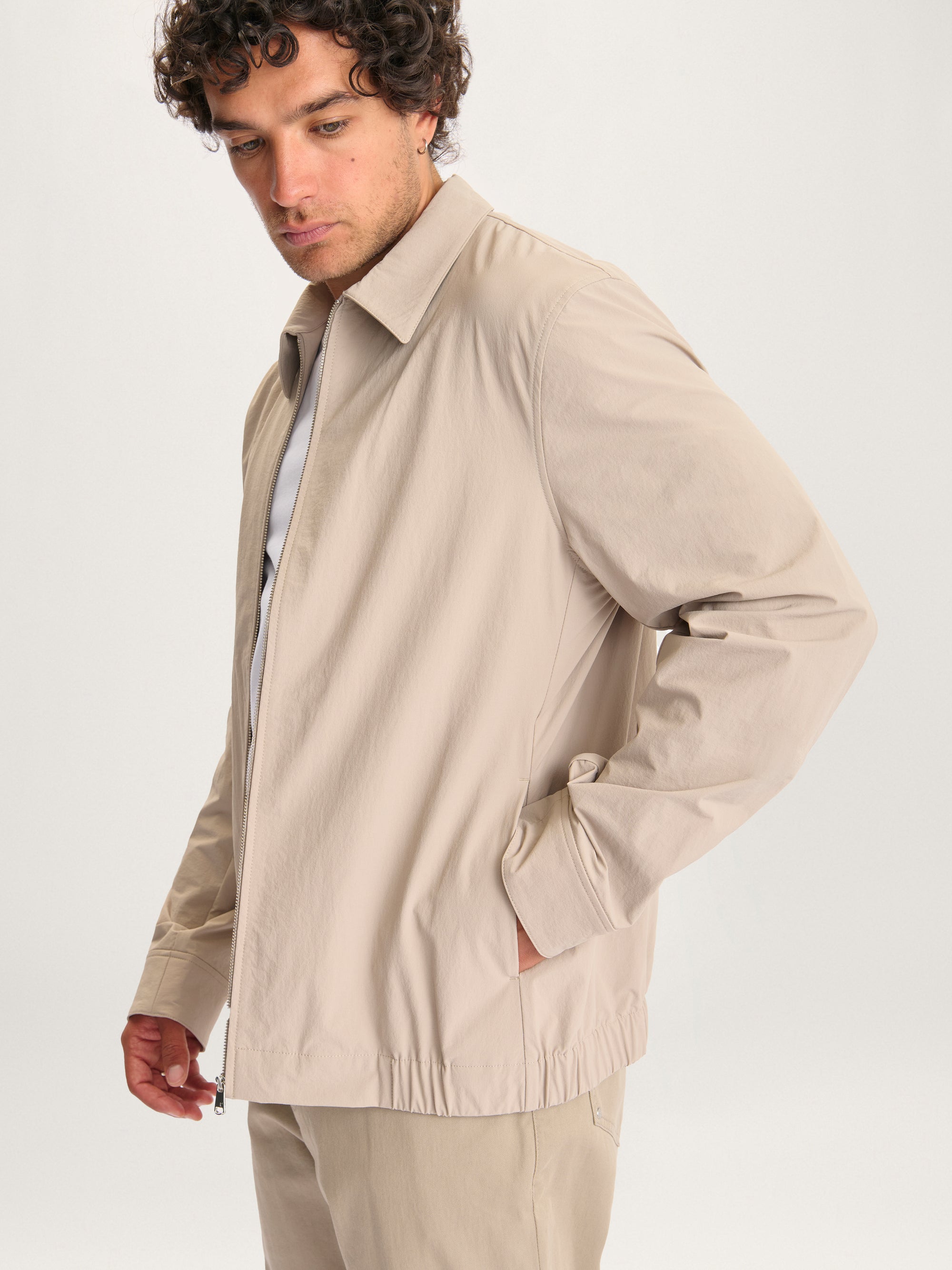 Side view of man wearing the Lestrange London 360 Jacket in beige with hands in pockets