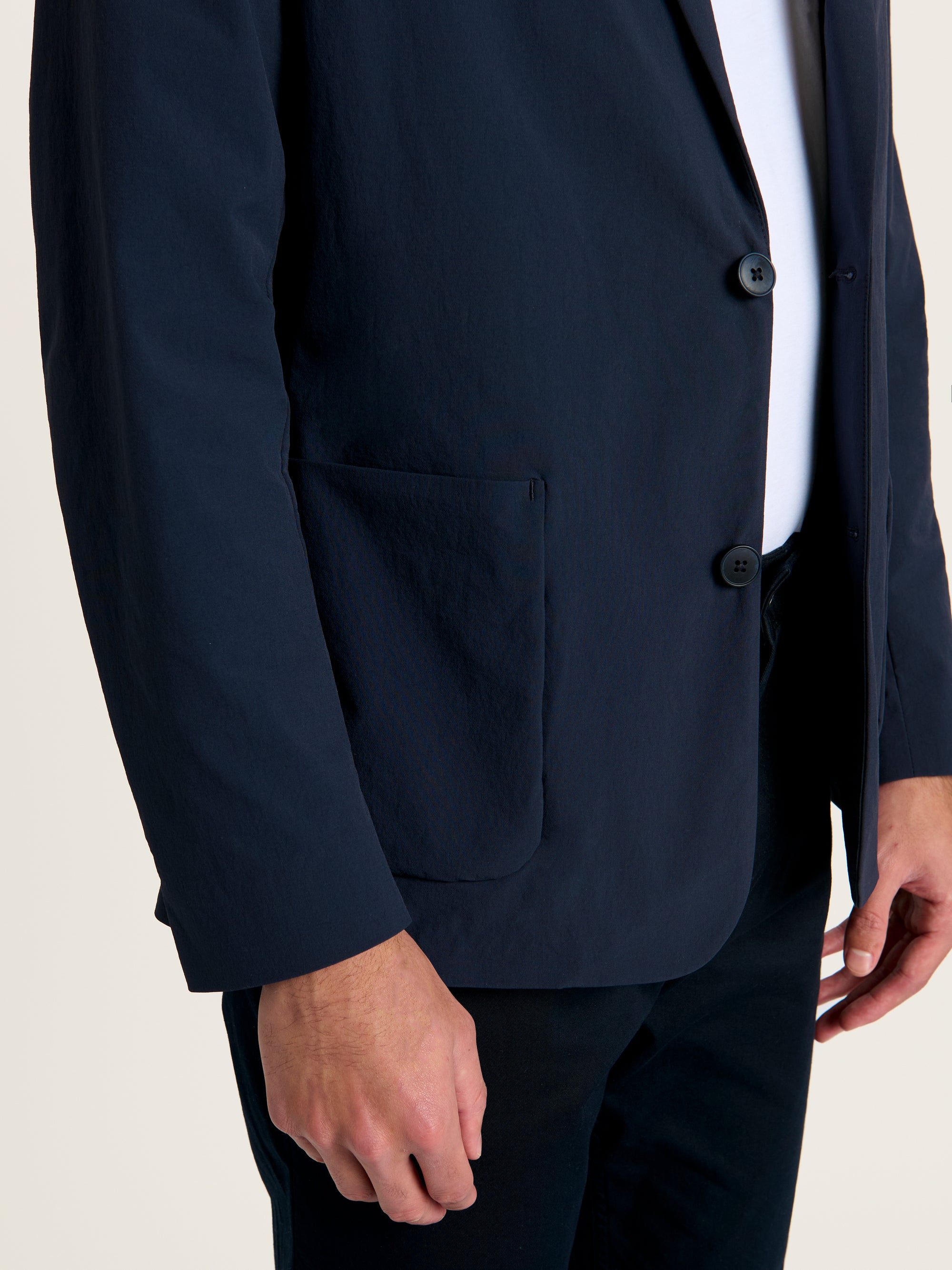 Close-up of Lestrange 360 Blazer in navy showing lightweight performance fabric, two-button fastening and front pocket detail for breathable, travel-ready menswear.