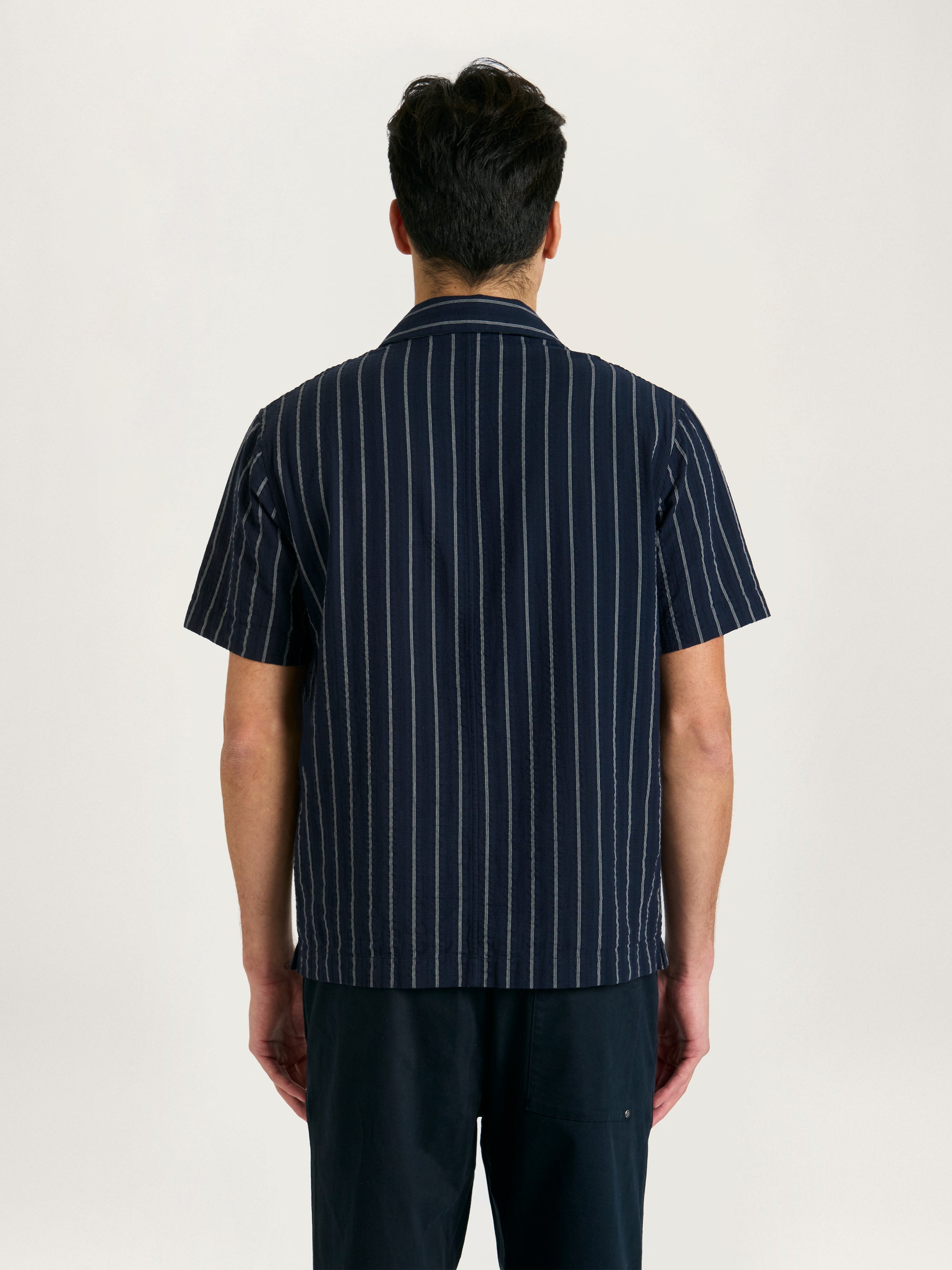 Back of men’s navy striped Cuban collar shirt with short sleeves and relaxed fit.