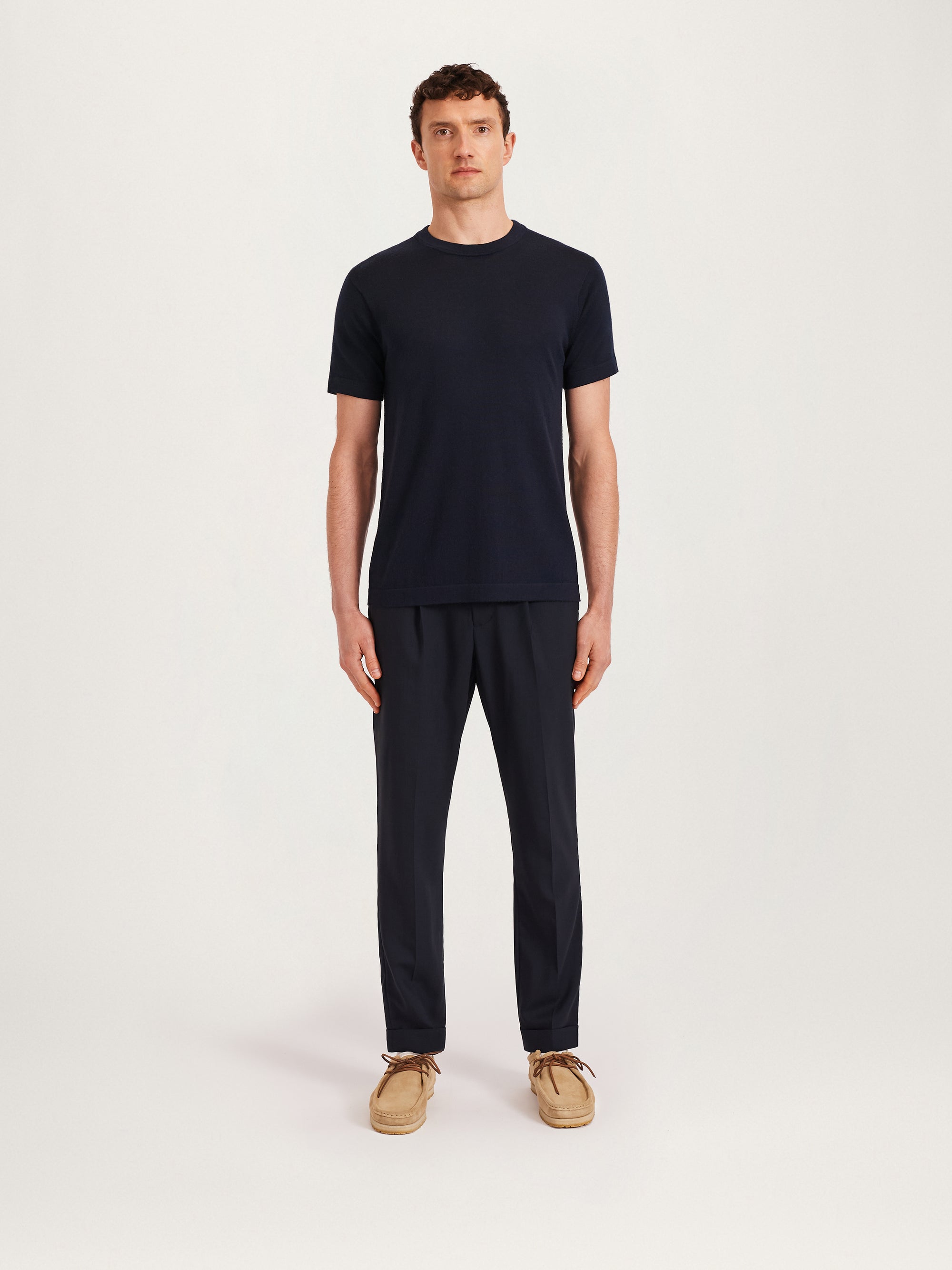 Men’s navy knitted T-shirt styled with navy tailored trousers and beige suede shoes – Lestrange London