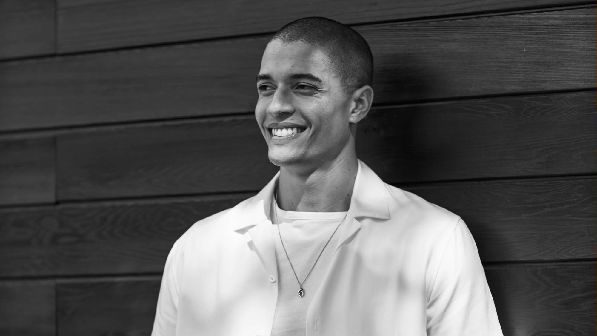 Man wearing a white shirt against a wooden wall