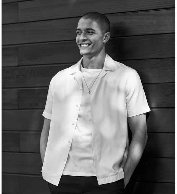 Man wearing a white shirt against a wooden wall