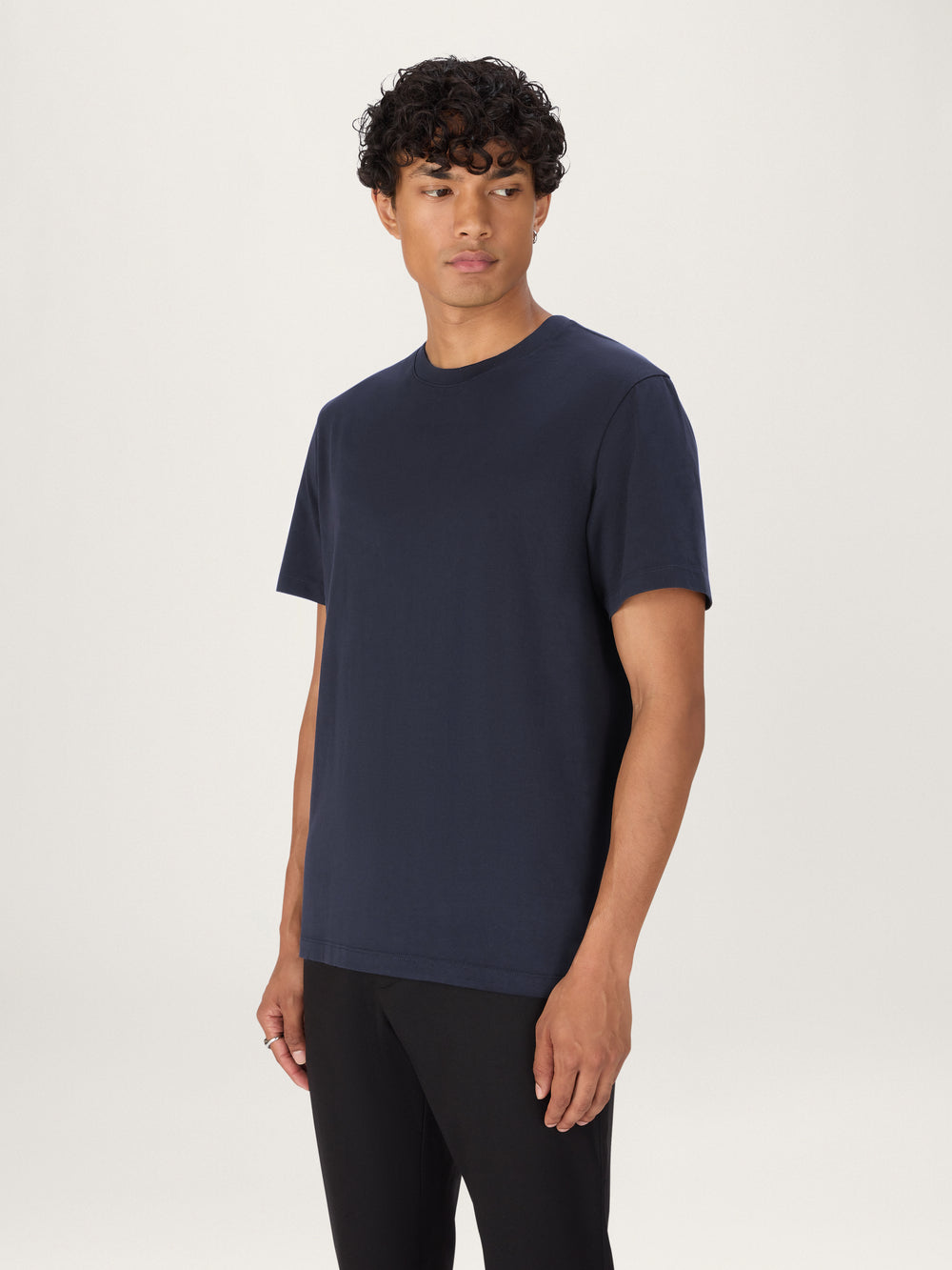 Man wearing a navy blue t-shirt and black pants on a white background