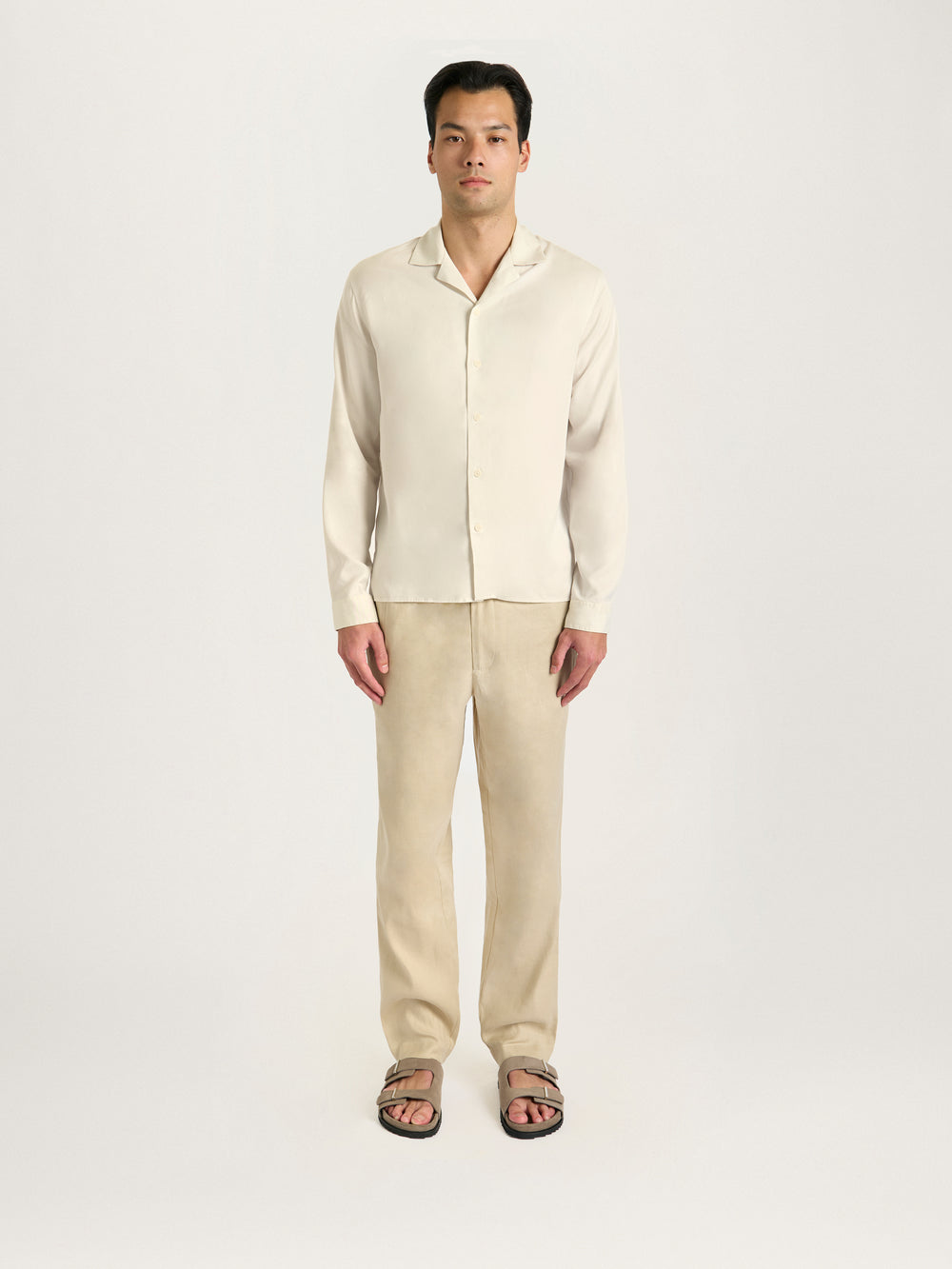 Man wearing a beige shirt and pants on a white background