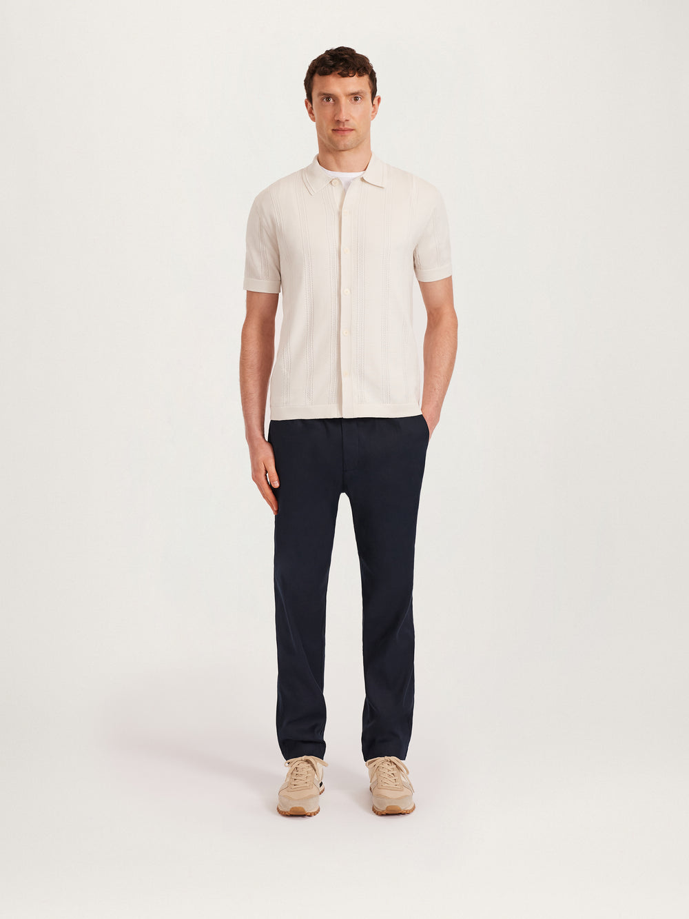 Men’s textured knit shirt in ecru with short sleeves, button front, and open collar.