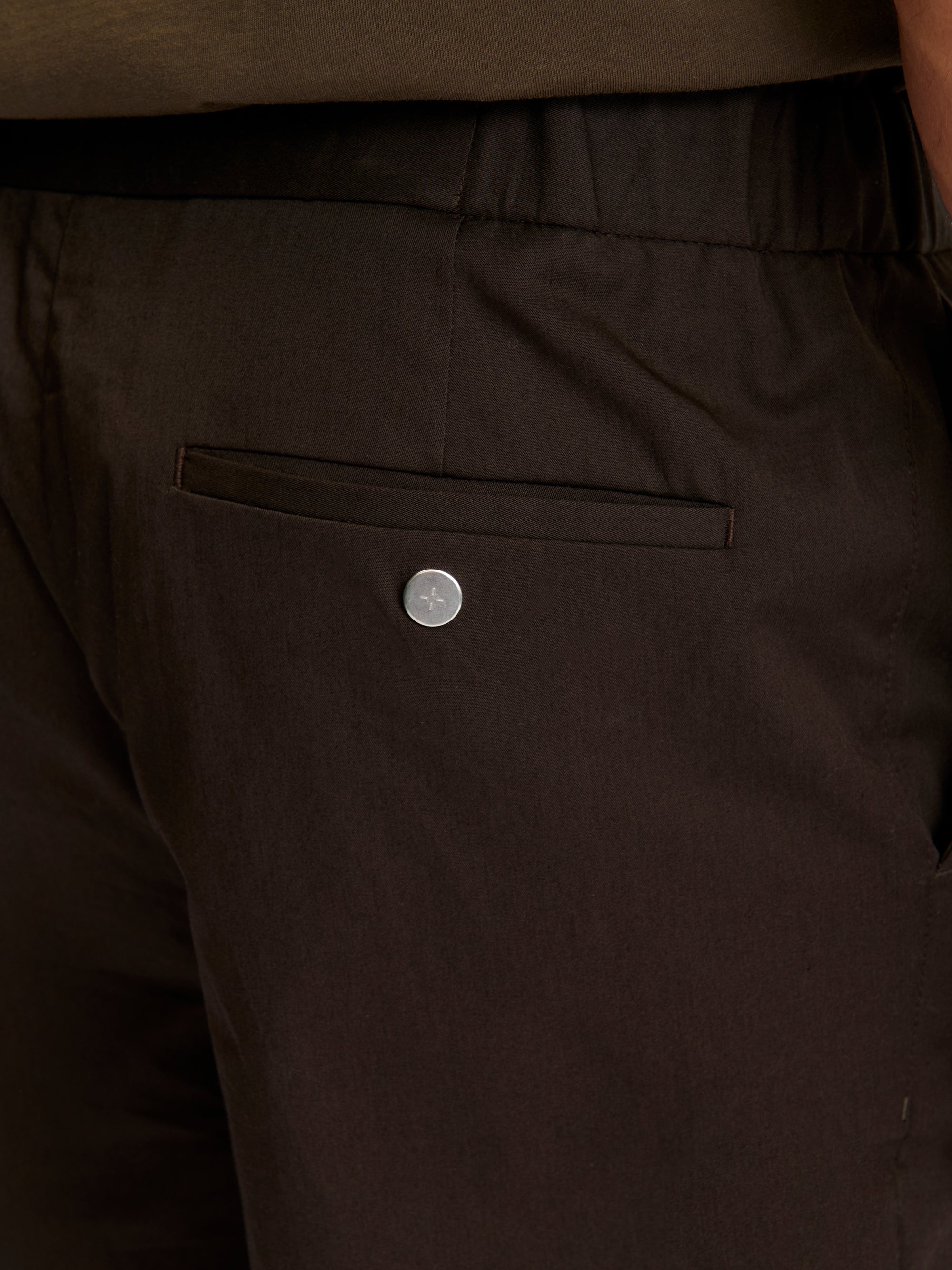 Close-up of Lestrange 24 Trouser Relaxed Espresso – rear pocket detail with branded button and premium cotton fabric texture.