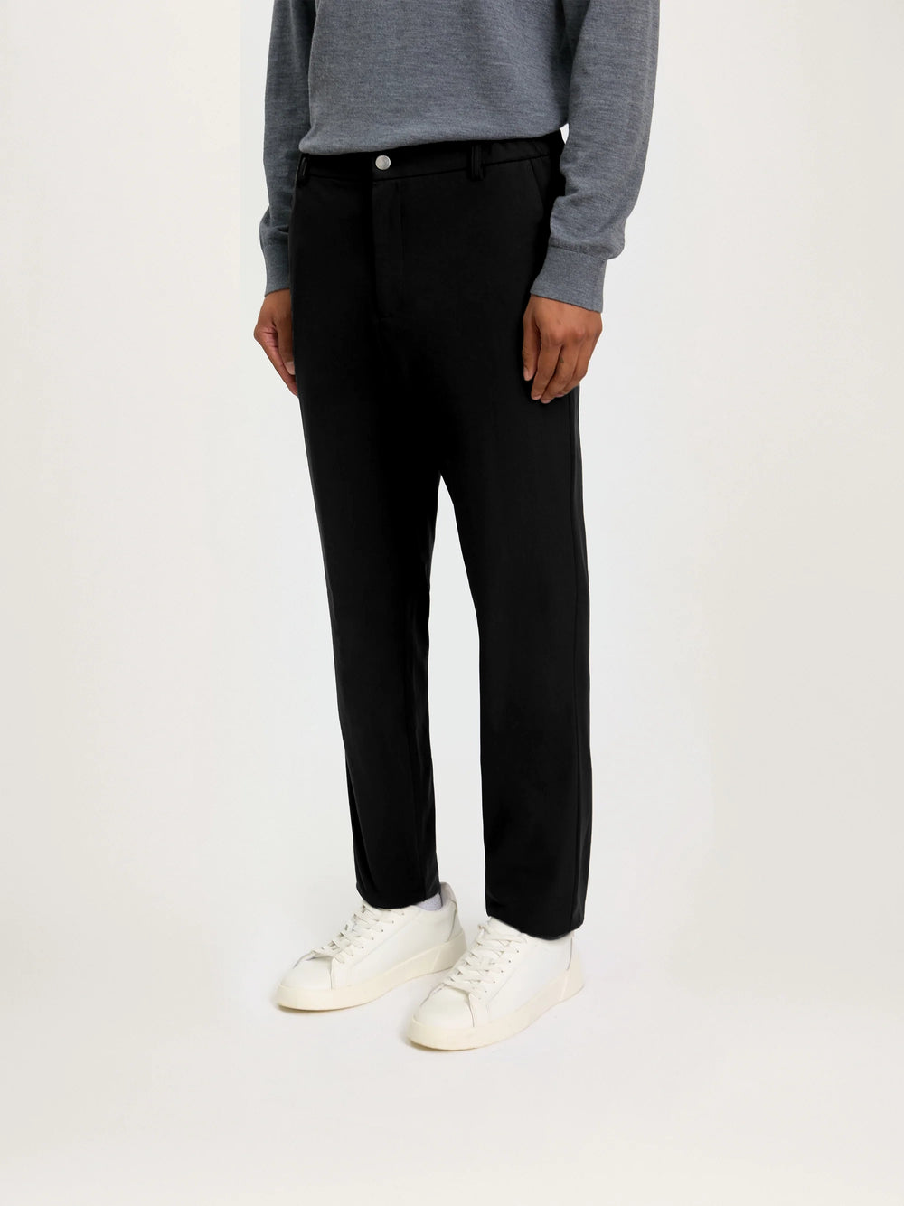 Person wearing black pants and a gray sweater on a white background