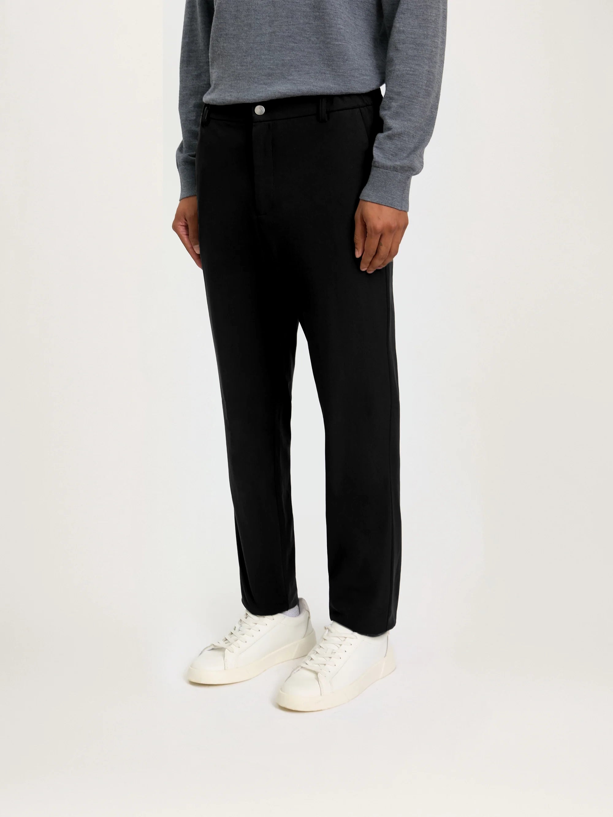 Person wearing black pants and a gray sweater on a white background