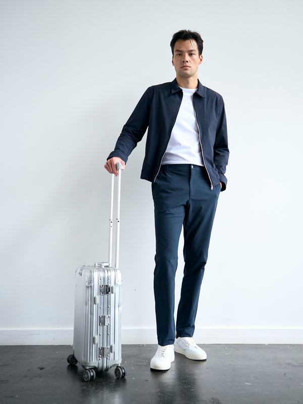 Man with a suitcase wearing the 360 Trouser in navy