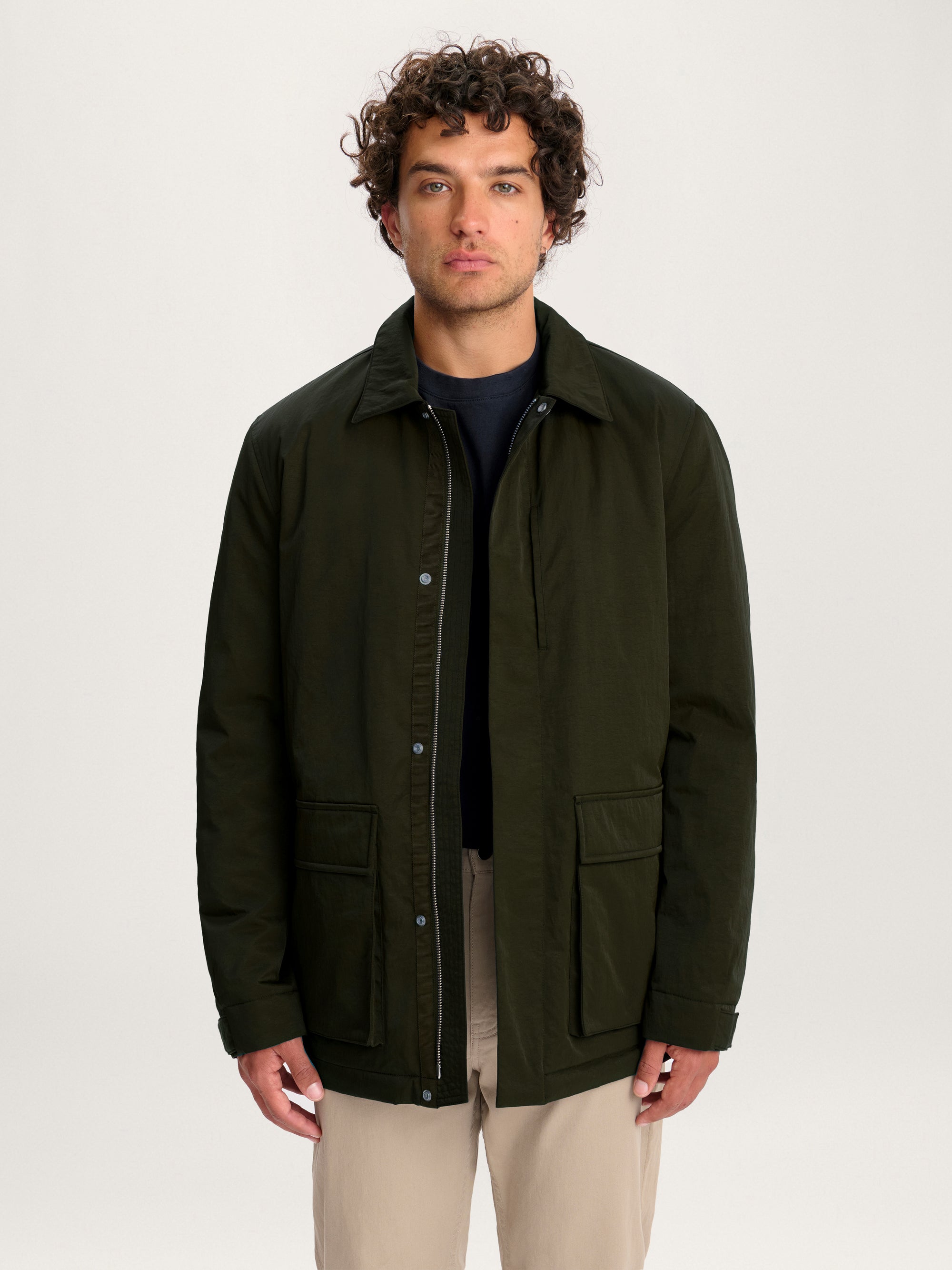 Front view of the men’s Lestrange Field Jacket in olive green with snap fastening and utility pockets.