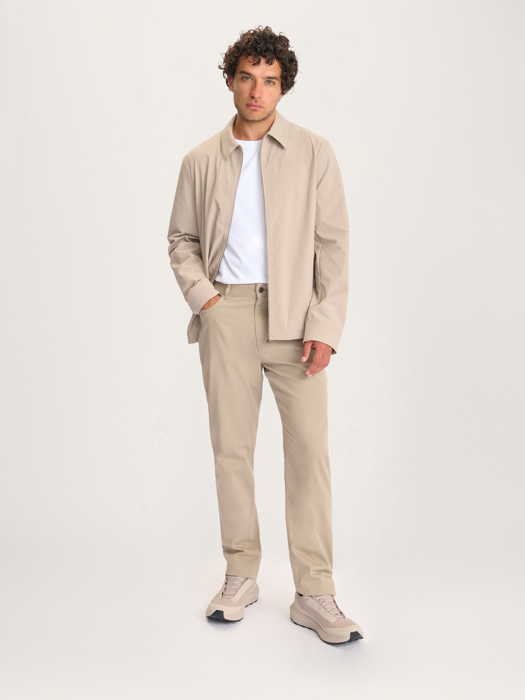 Full-body view of man wearing the Lestrange London 360 Jacket in beige with matching trousers and sneakers