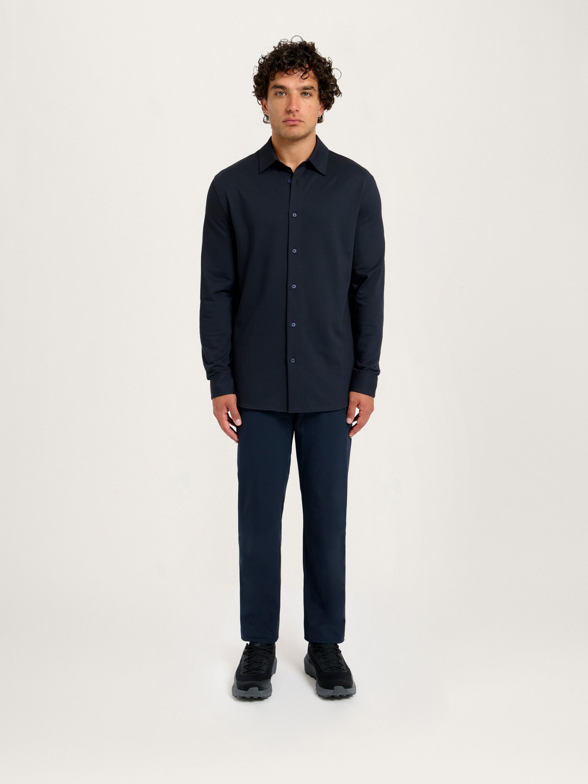 Model in relaxed pose wearing Lestrange London 360 Mesh Tech Shirt navy, styled with tailored navy trousers and sneakers