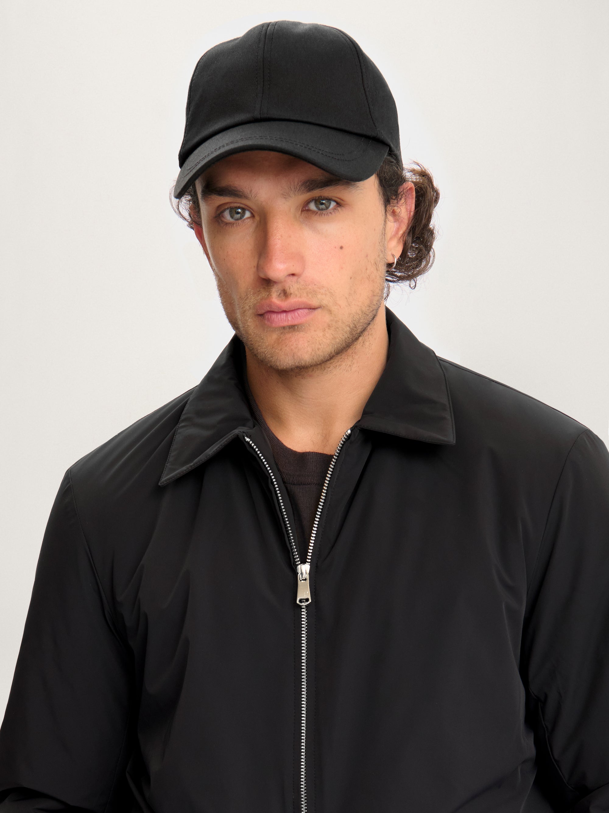 Close-up of model wearing Lestrange 360 Thermal Jacket in black, minimalist insulated outerwear with pointed collar and silver zipper."