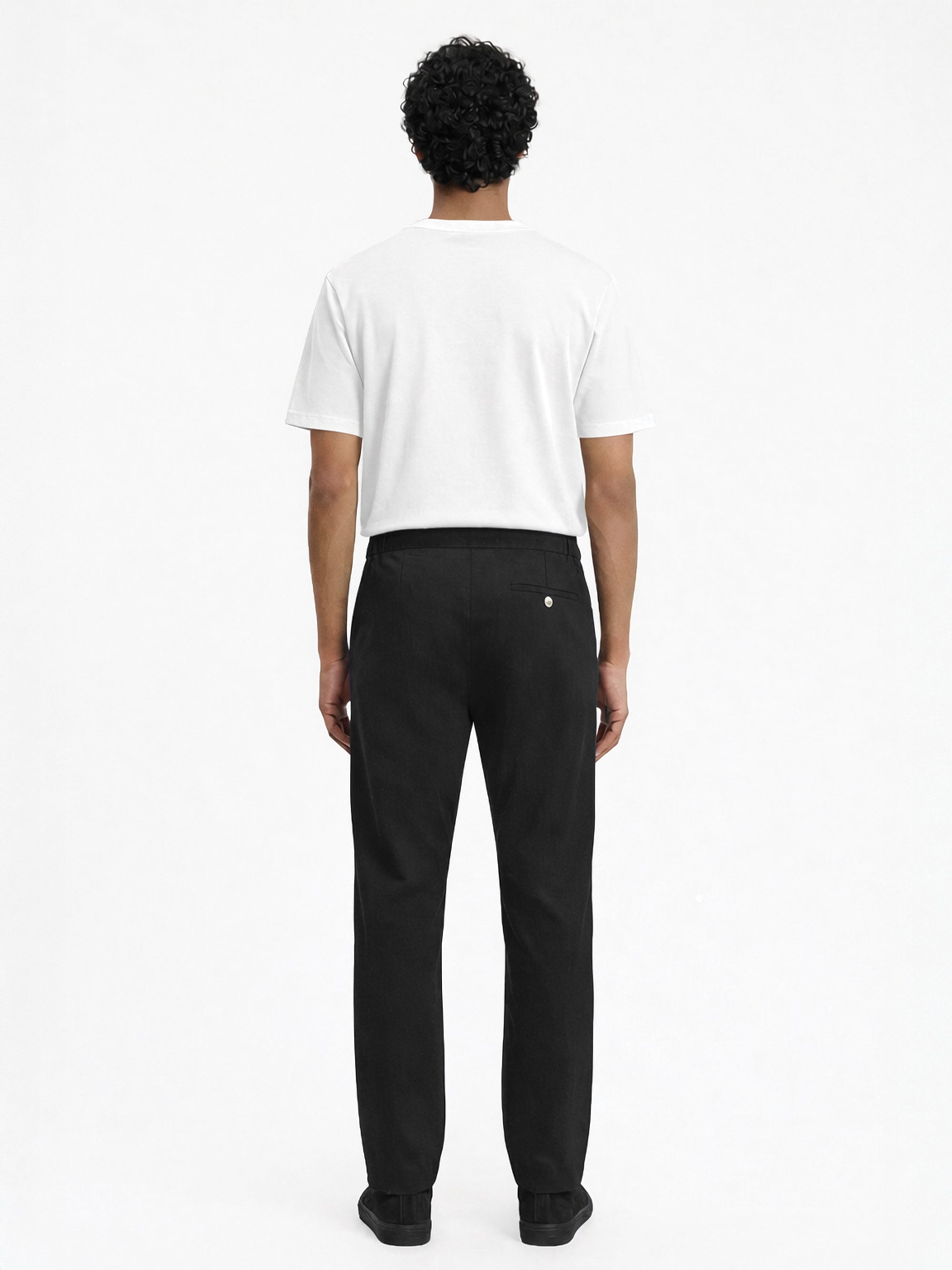 Back view of LESTRANGE black trousers worn with a white t-shirt, featuring a clean rear profile, back pocket detail, and smart casual fit.