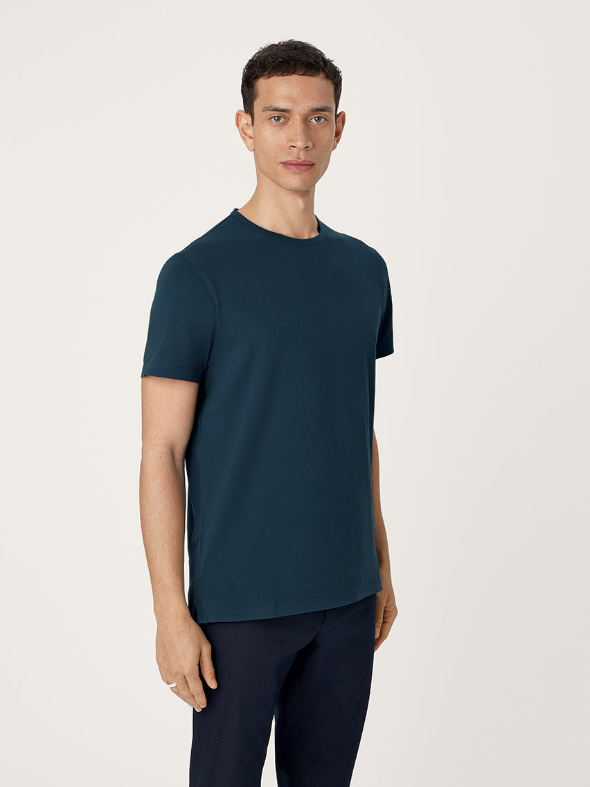 Man wearing a pebble blue t-shirt and black pants on a light background