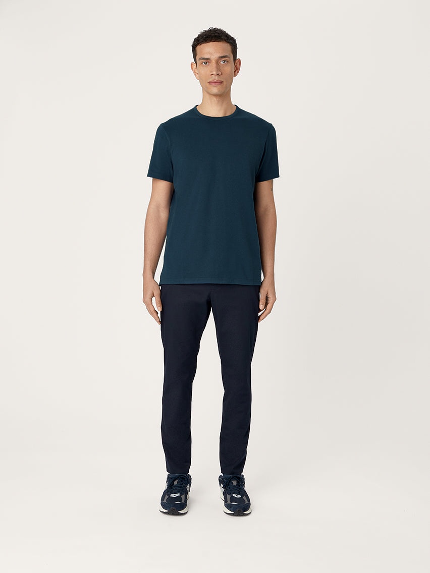 Man wearing a dark blue t-shirt and pants on a white background