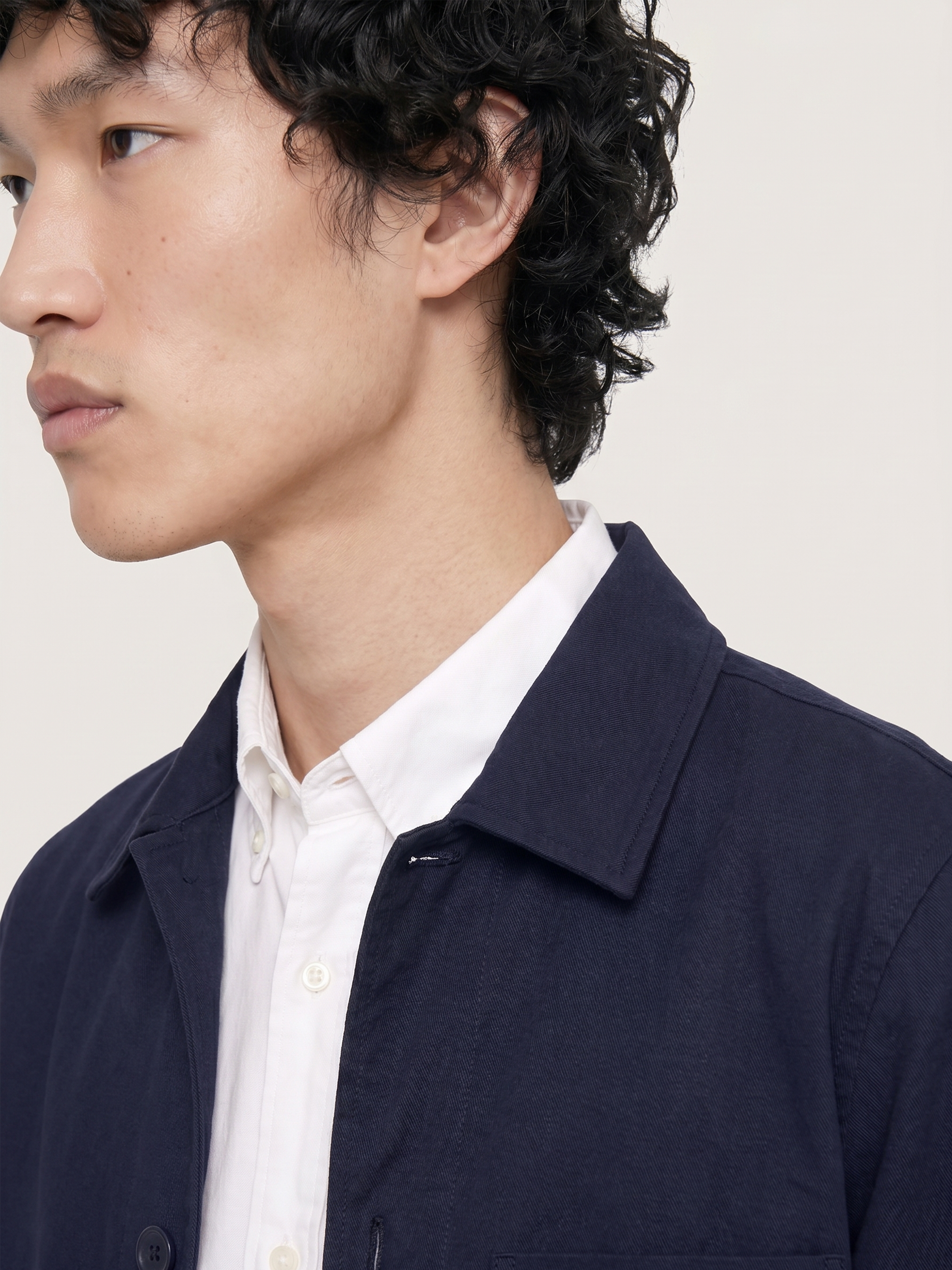 Close-up of the LESTRANGE navy overshirt collar, showing the textured cotton fabric layered over a white shirt.