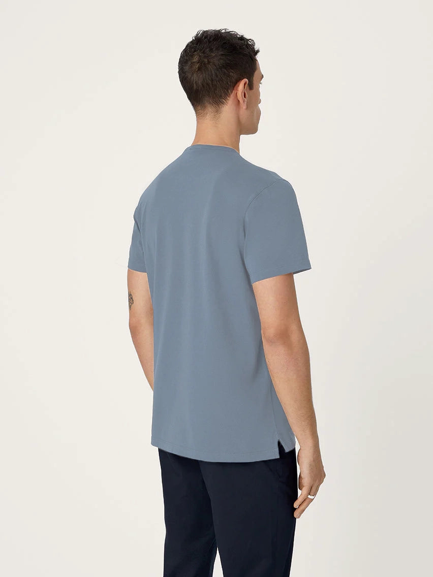 Person wearing a light blue t-shirt and dark pants on a white background