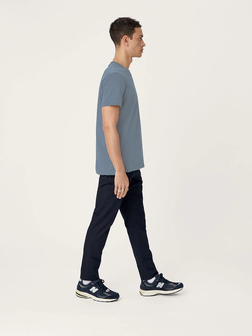 Man wearing a blue t-shirt and black pants walking on a white background
