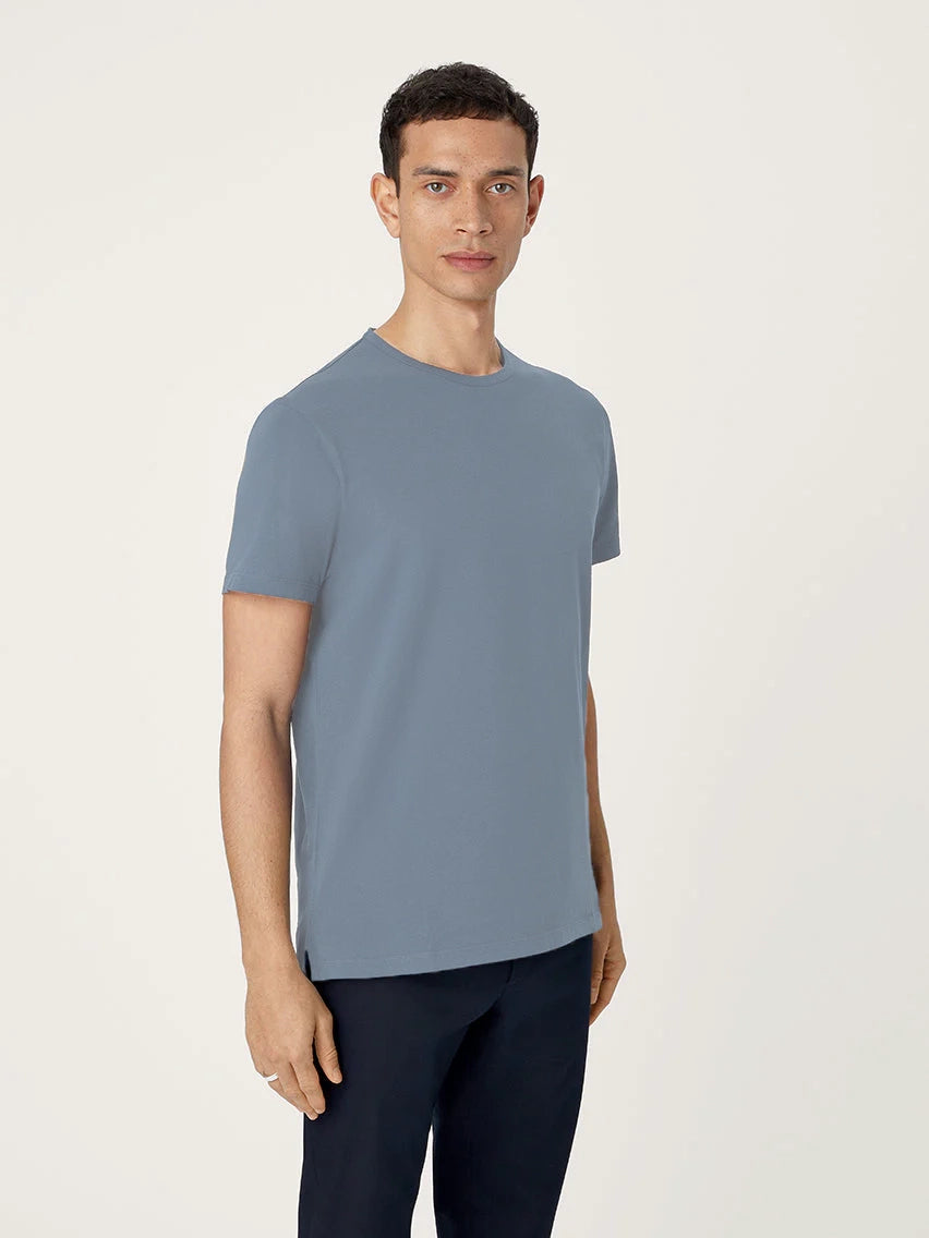 Man wearing a light blue t-shirt and dark pants on a plain background