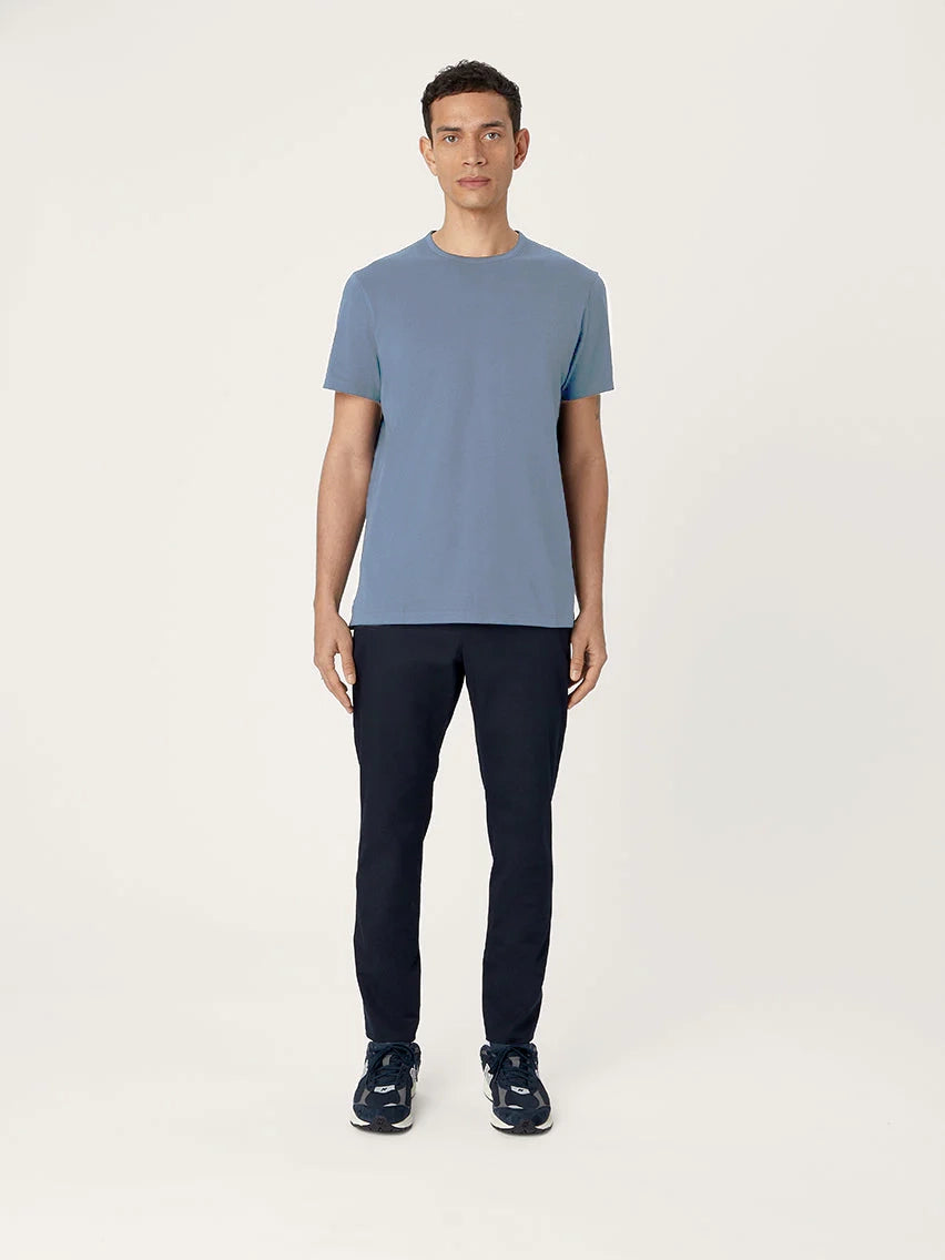 Man wearing a blue t-shirt and black pants on a white background