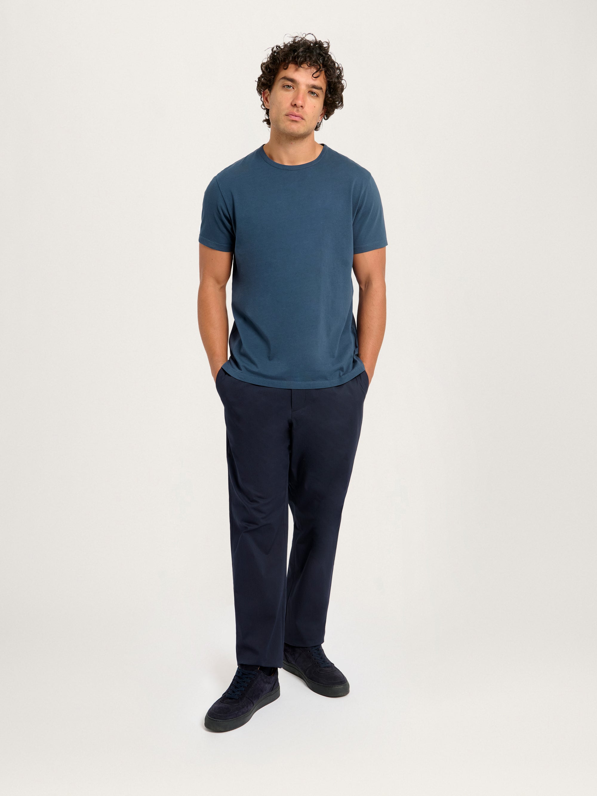 Angled view of Lestrange London Classic Tee in Pebble styled with navy trousers
