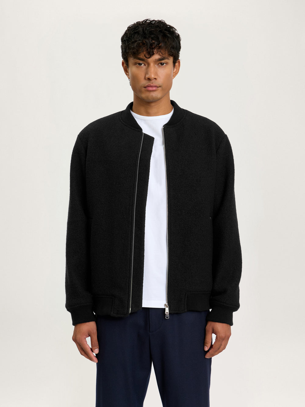 Close-up side view of the Lestrange London Cloud Wool Bomber in black, showing soft textured wool fabric and silver zip detailing.