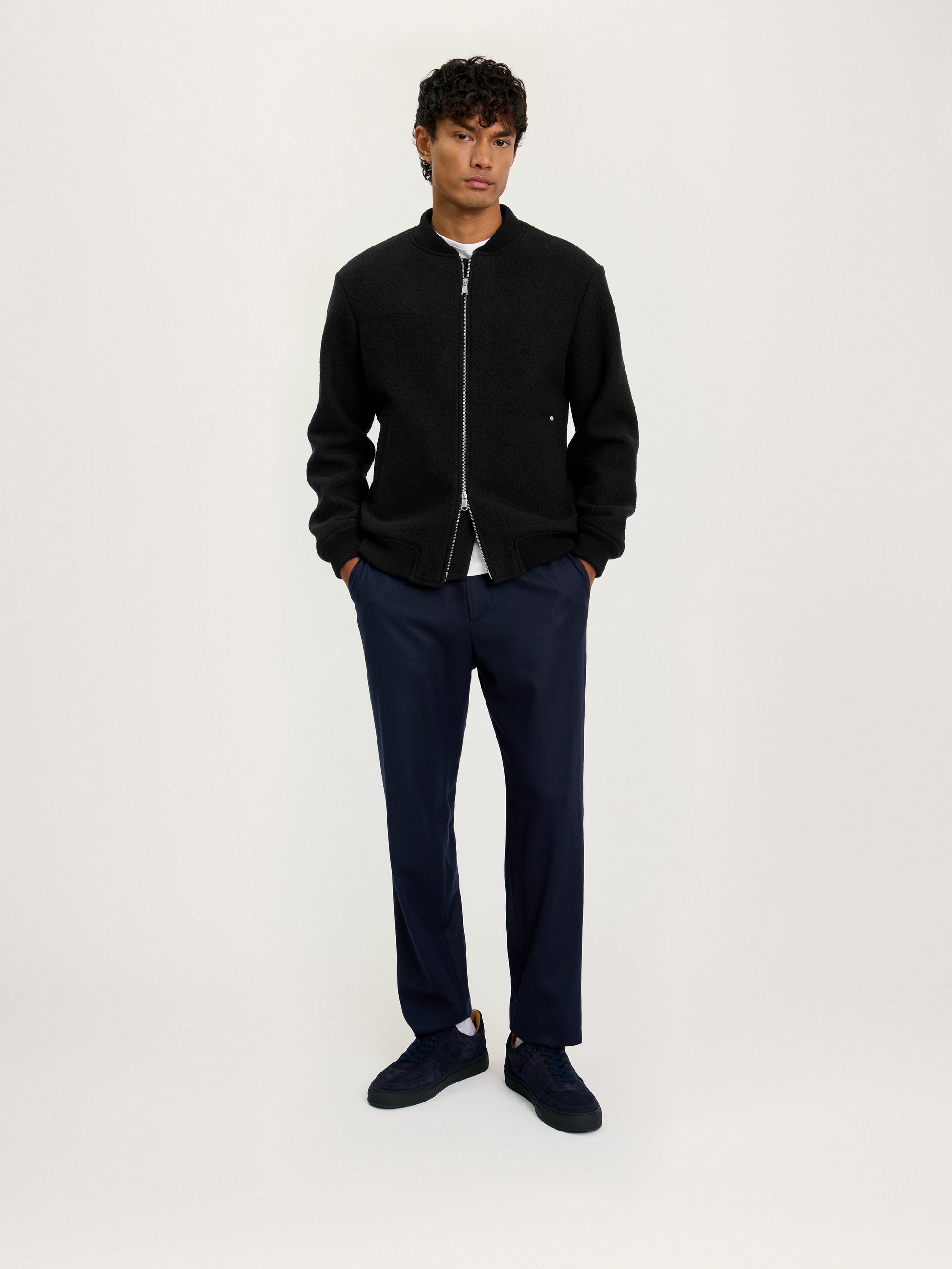 Lifestyle shot of model wearing the Lestrange London Cloud Wool Bomber in black with navy trousers and sneakers — relaxed everyday look.