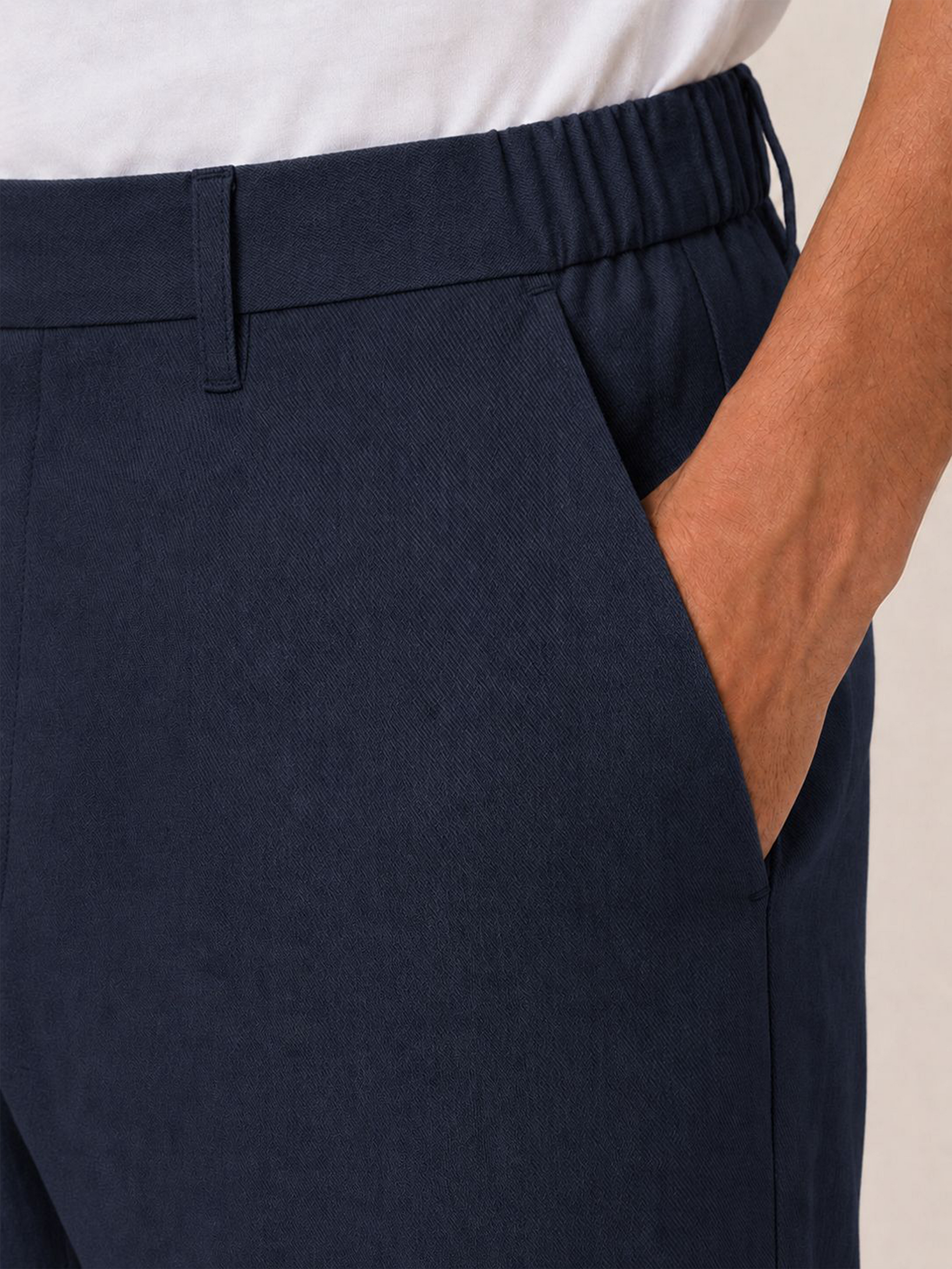 Close-up of the LESTRANGE regular navy linen trouser waistband, showing the elasticated side panel, belt loop and textured linen fabric.