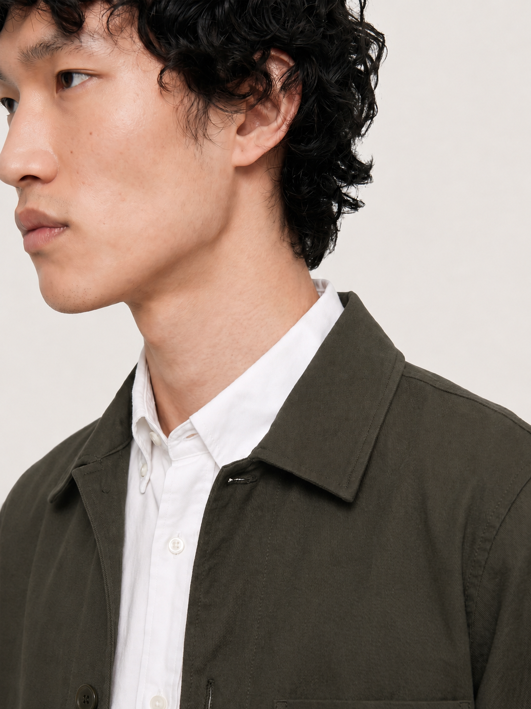 Close-up of the LESTRANGE dark olive overshirt collar, showing the textured fabric and button-front construction over a white shirt.