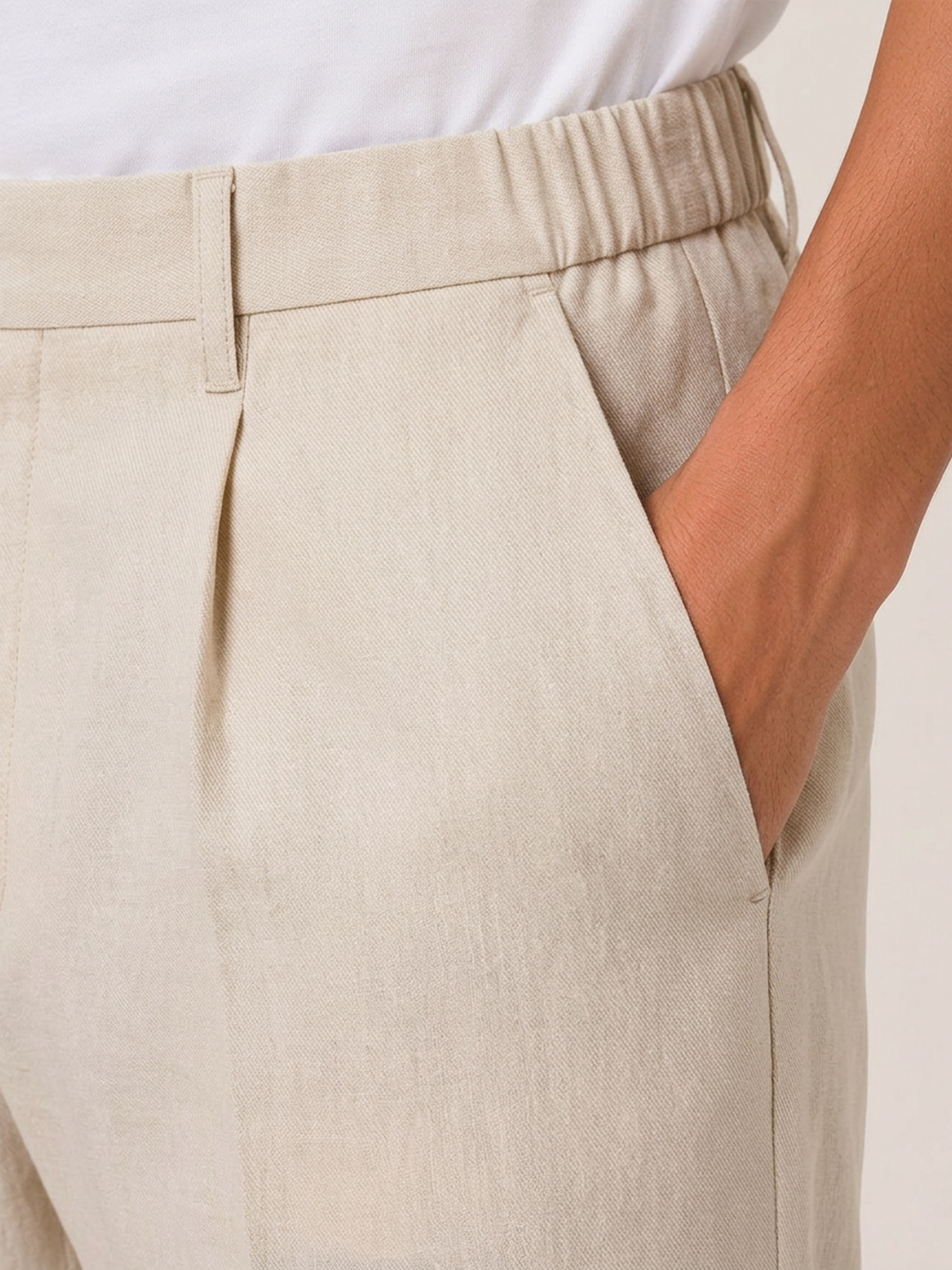 Close-up of the LESTRANGE natural beige linen trouser waistband, showing the elasticated side panel, belt loop and textured linen fabric.