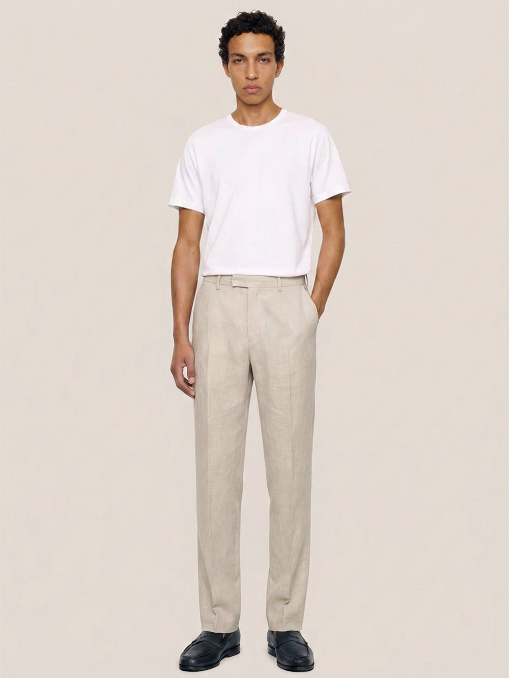 Front view of the LESTRANGE regular natural beige linen trousers styled with a white T-shirt and black leather loafers.
