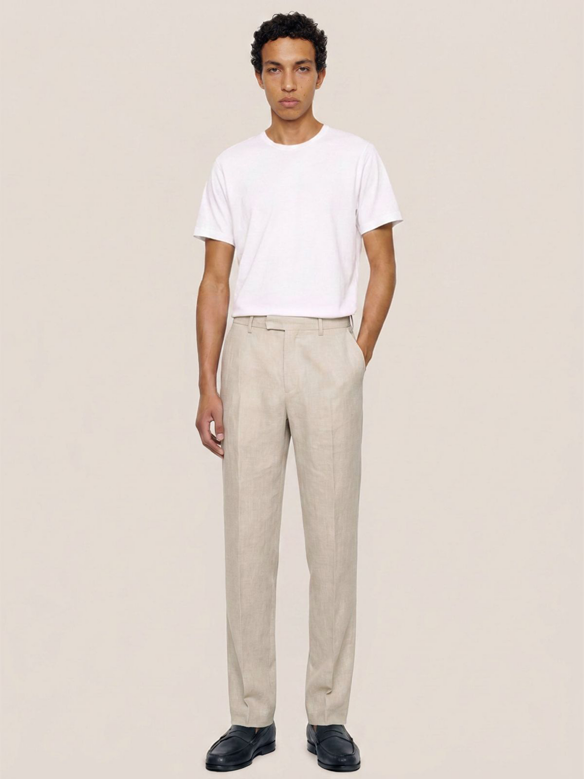 Front view of the LESTRANGE regular natural beige linen trousers styled with a white T-shirt and black leather loafers.