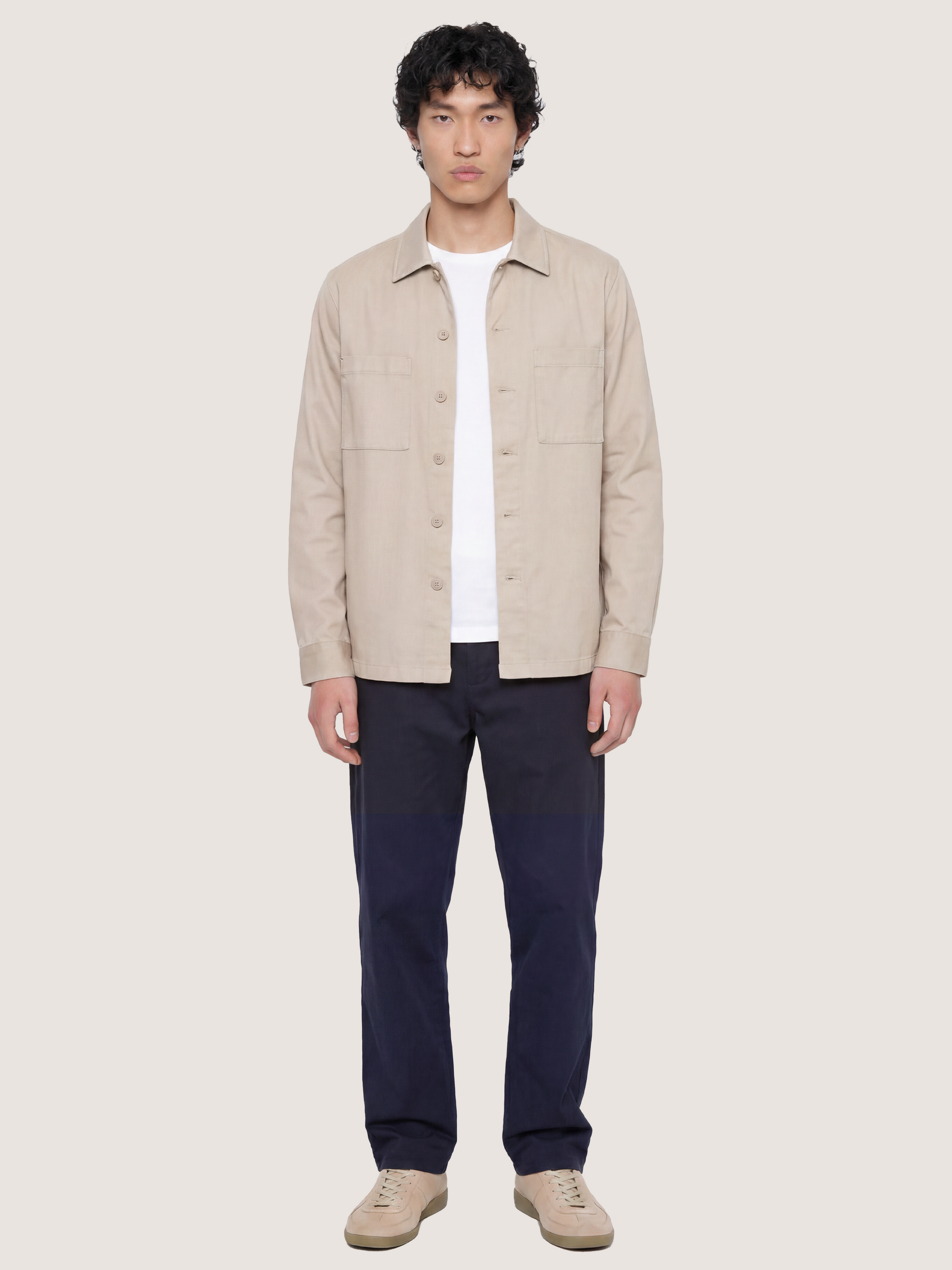 Front view of the LESTRANGE beige overshirt styled open over a white T-shirt with navy trousers.