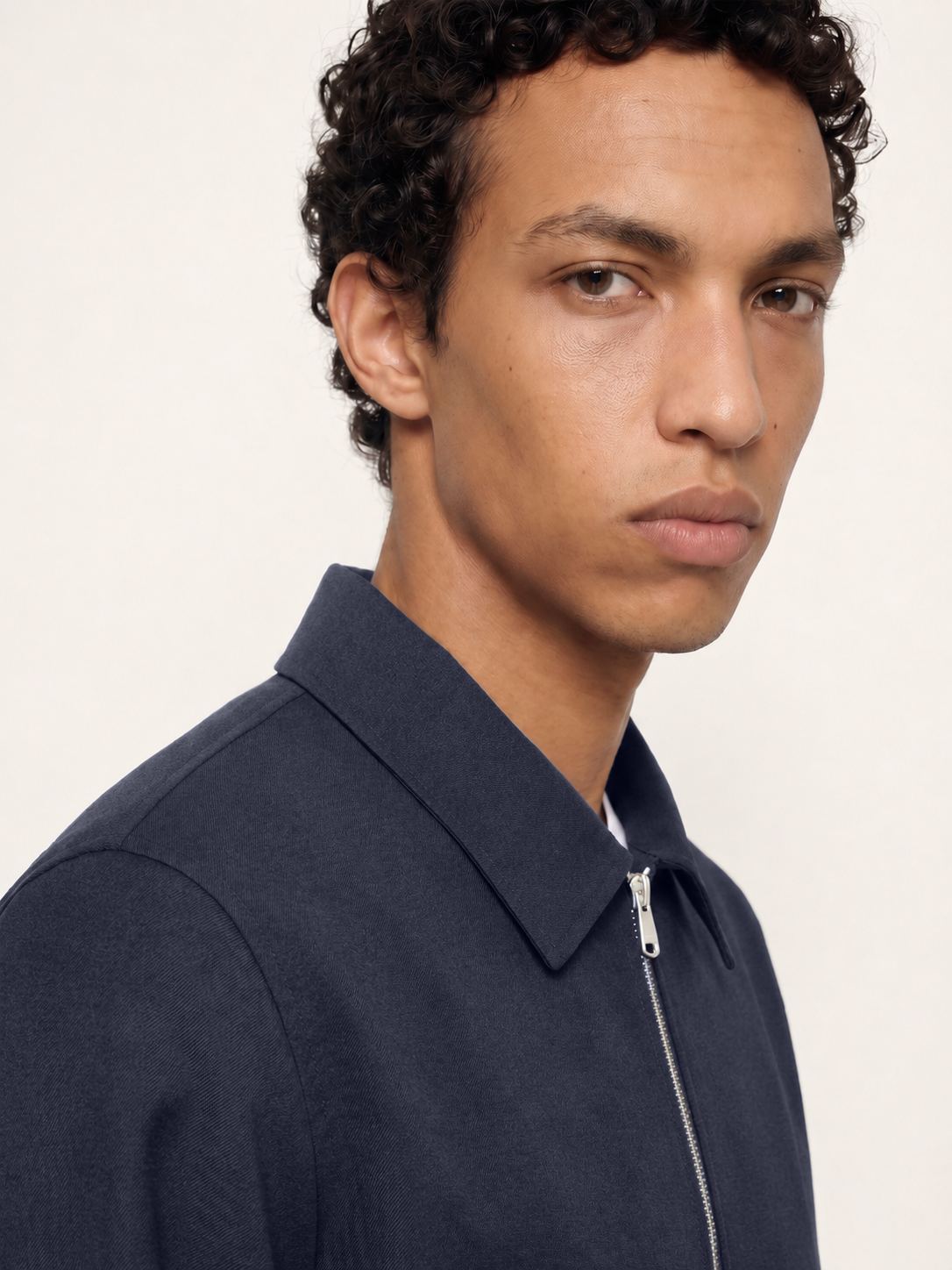 Close-up of The 24 Coach Jacket in navy cotton, showing the pointed collar, zip fastening and smooth cotton fabric.