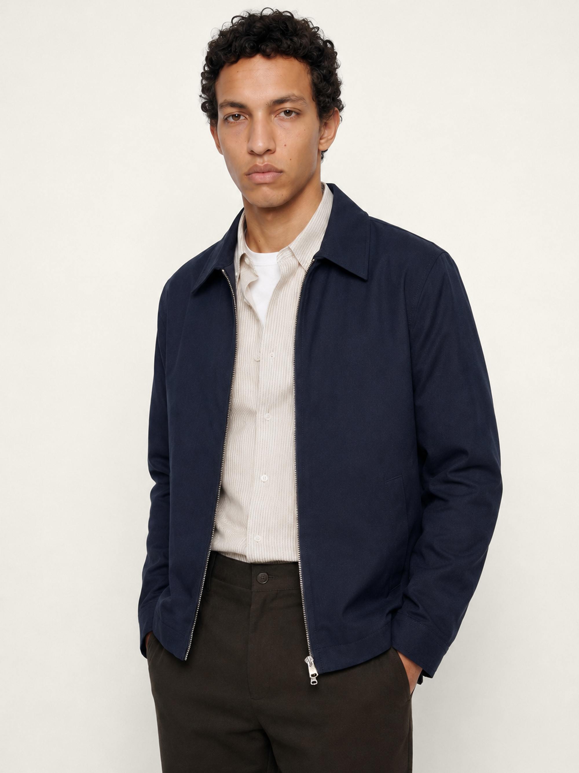Three-quarter view of The 24 Coach Jacket in navy cotton, showing the zip front, clean silhouette and side pocket detail.