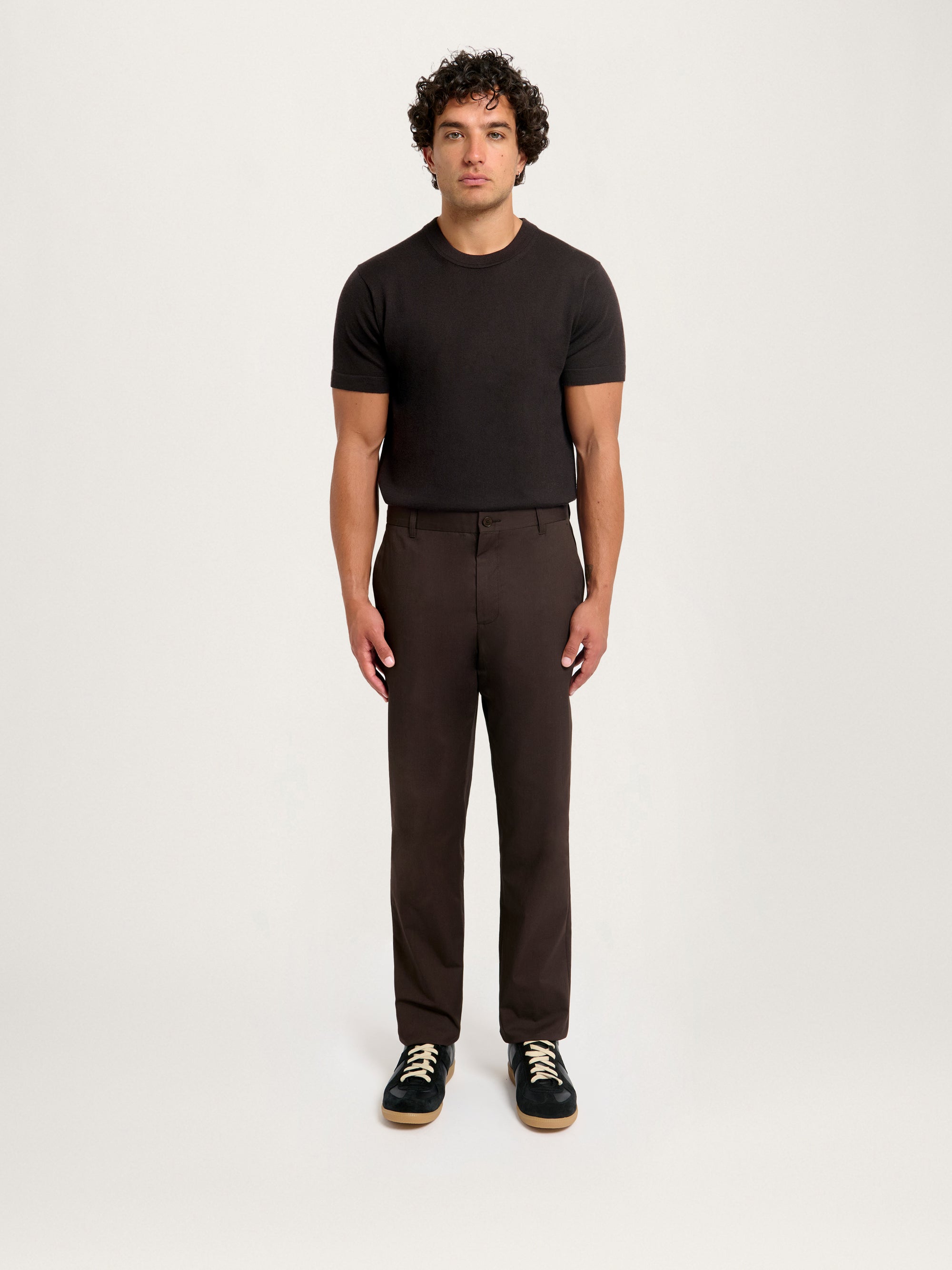 Model wearing Lestrange London Essential Chino in espresso brown, styled with black knit T-shirt and sneakers