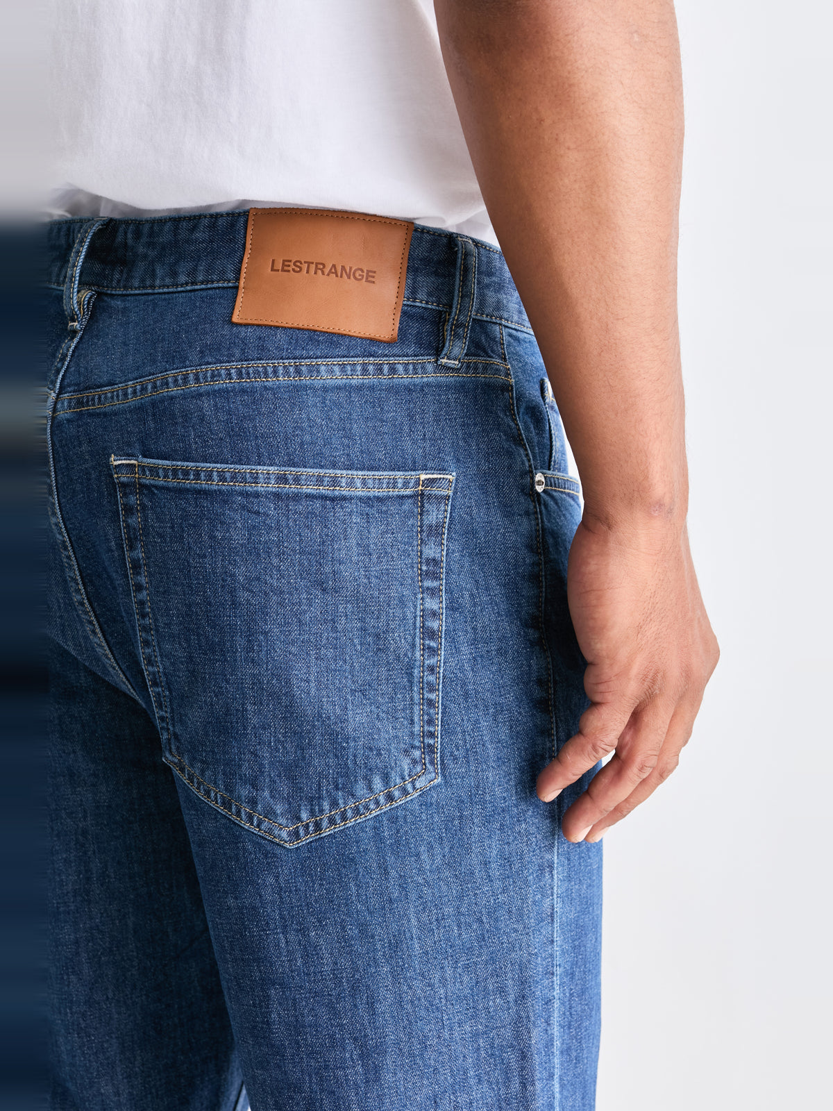 The 24 Jeans Straight Fit in Mid Blue, close-up of back pocket, stitching and LESTRANGE leather patch